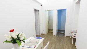A small, bright room with a white table, chairs, and a vase of white flowers. There are doors leading to other rooms. - Buonanotte Roma 2 (Rome)