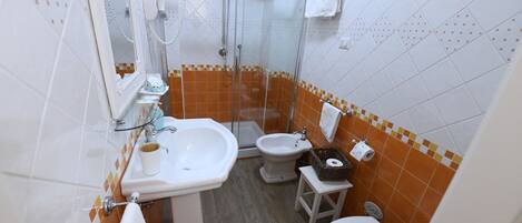 Ein Badezimmer mit Dusche, Toilette, Bidet und Waschbecken.