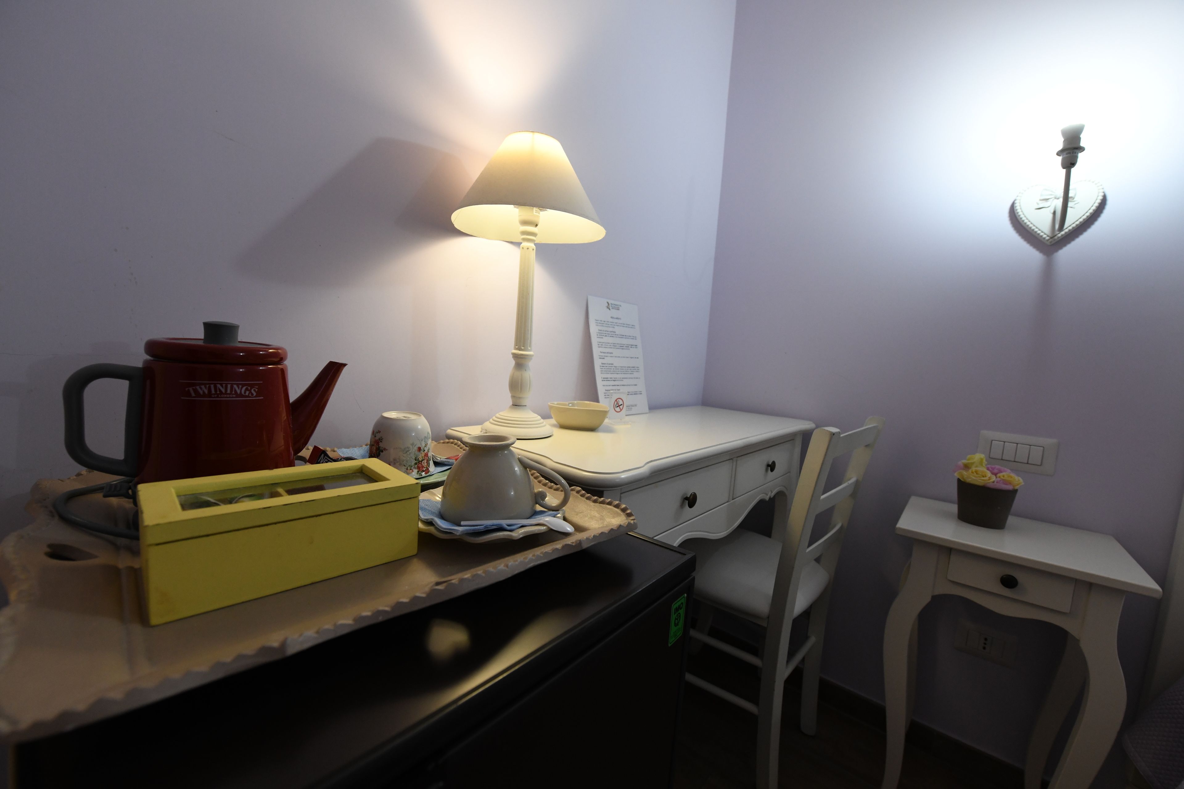 A small kitchenette with a coffee maker, a lamp, a bowl, and a tray.