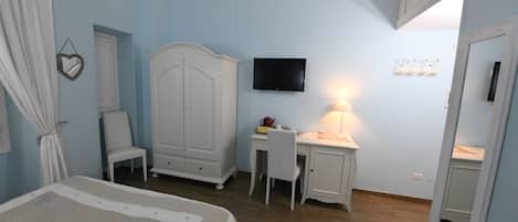 Un dormitorio con cama, escritorio, silla, armario, televisor y espejo.