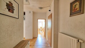 A hallway with wooden flooring, a radiator, and framed artwork on the walls. - Jacob´s Resort House Podkoren (Kranjska Gora)