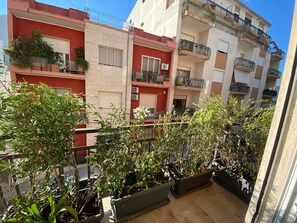 Un edificio residencial con balcones, plantas en macetas y cielo despejado.