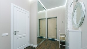 A hallway with a white door, a large mirror, and a wooden floor. - VIP Apartment Company (Kyiv)