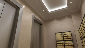A hotel room with a modern ceiling design, recessed lighting, and a wall-mounted storage unit. - VIP Apartment Company (Kyiv)