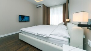 A modern hotel room with a large bed, a flat-screen TV, a bedside lamp, and an air conditioning unit. - VIP Apartment Company (Kyiv)
