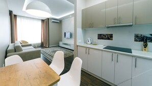 A modern hotel room with a dining area, a sofa, a TV, and a kitchen with cabinets and a countertop. - VIP Apartment Company (Kyiv)