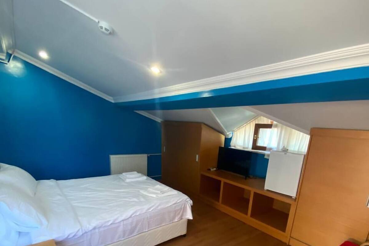 A hotel room with a bed, a desk, a chair, a wardrobe, and a television.
