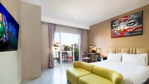 Une chambre d’hôtel avec un grand lit, un canapé jaune, une télévision et un tableau au mur.