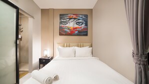 Une chambre d’hôtel avec un lit, une table de chevet, un tableau et un espace douche.