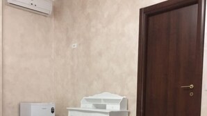 A room with a marble floor, a white desk, a small white refrigerator, and a wooden door. - B&B Arcobaleno (Gallipoli)