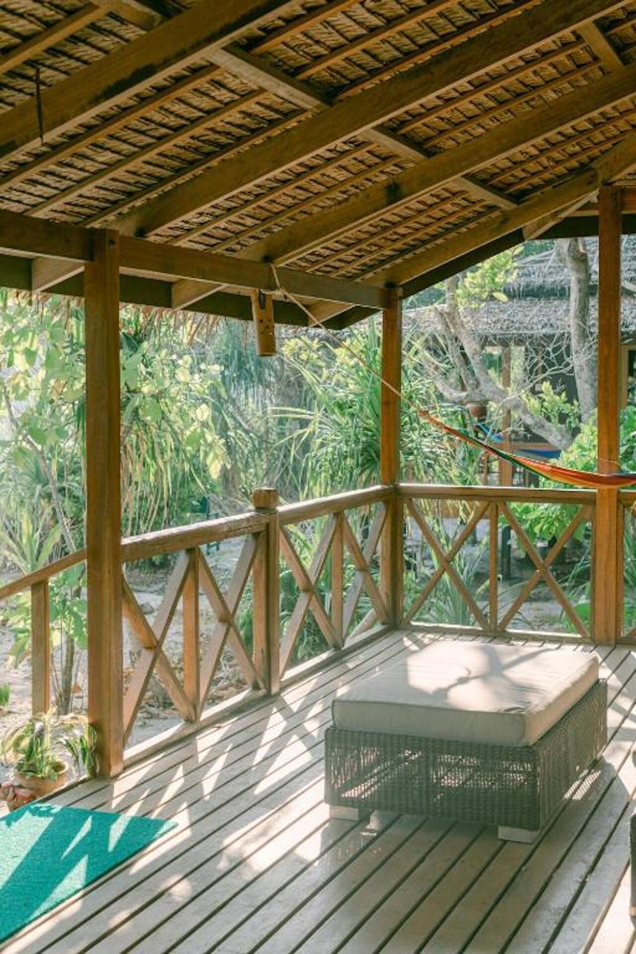A wooden deck with a woven bench and a hammock.