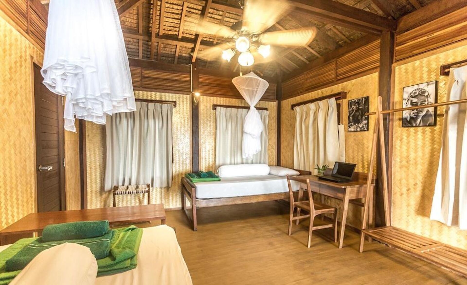 Une pièce comprenant un lit, un bureau, une chaise et un ventilateur de plafond.