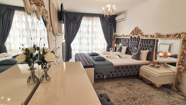 A bedroom with a large bed, a vanity with a mirror, a dresser, and a chandelier. - Megas Palace Bankya (Sofia)
