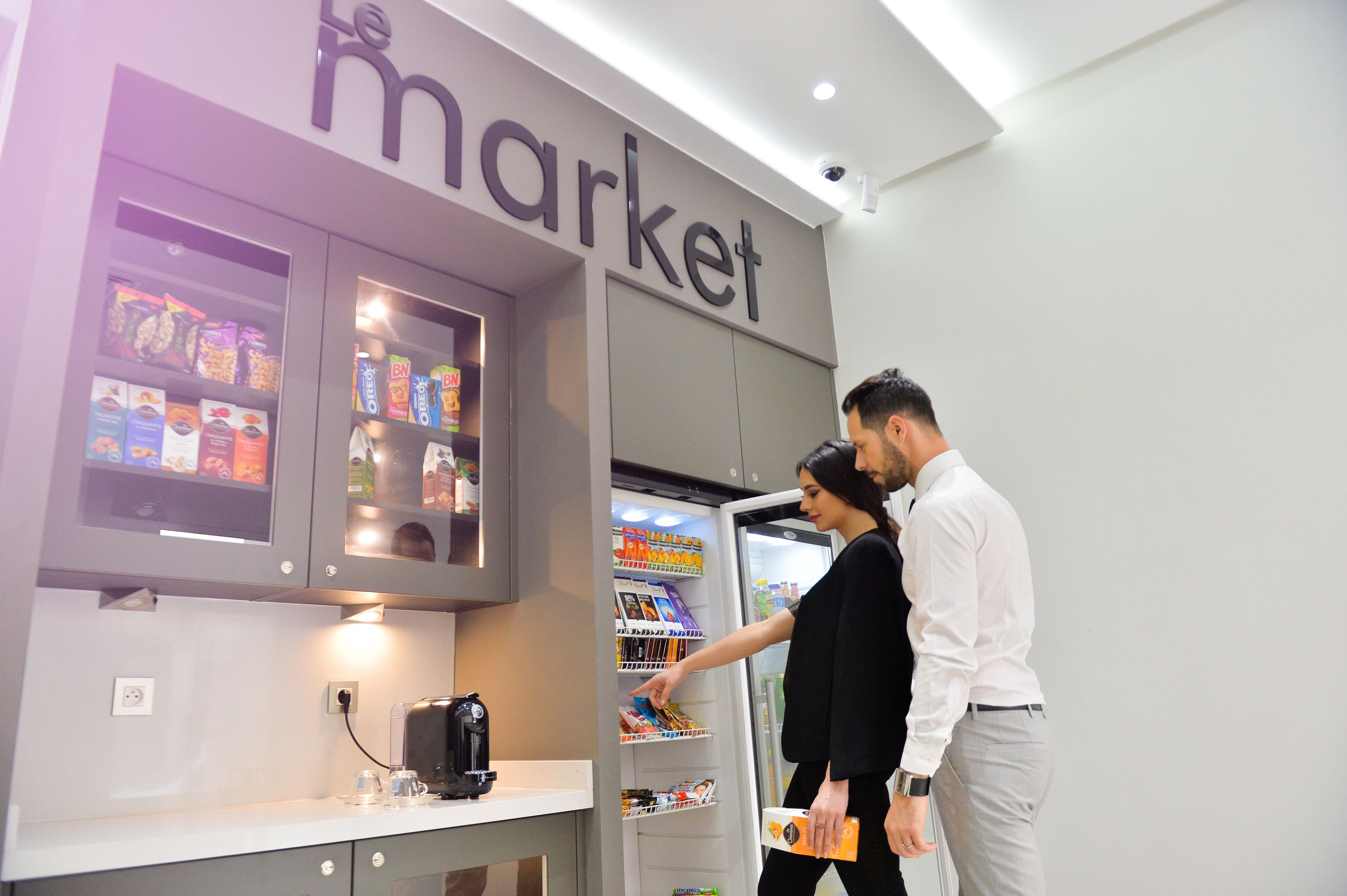 Un mercado con estantes llenos de aperitivos y una máquina de café en la barra.