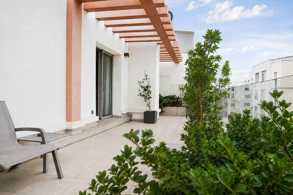 A balcony with a bench, potted plants, and a view of neighboring buildings. - Le 22 Appart' Hôtel Casablanca (Casablanca)