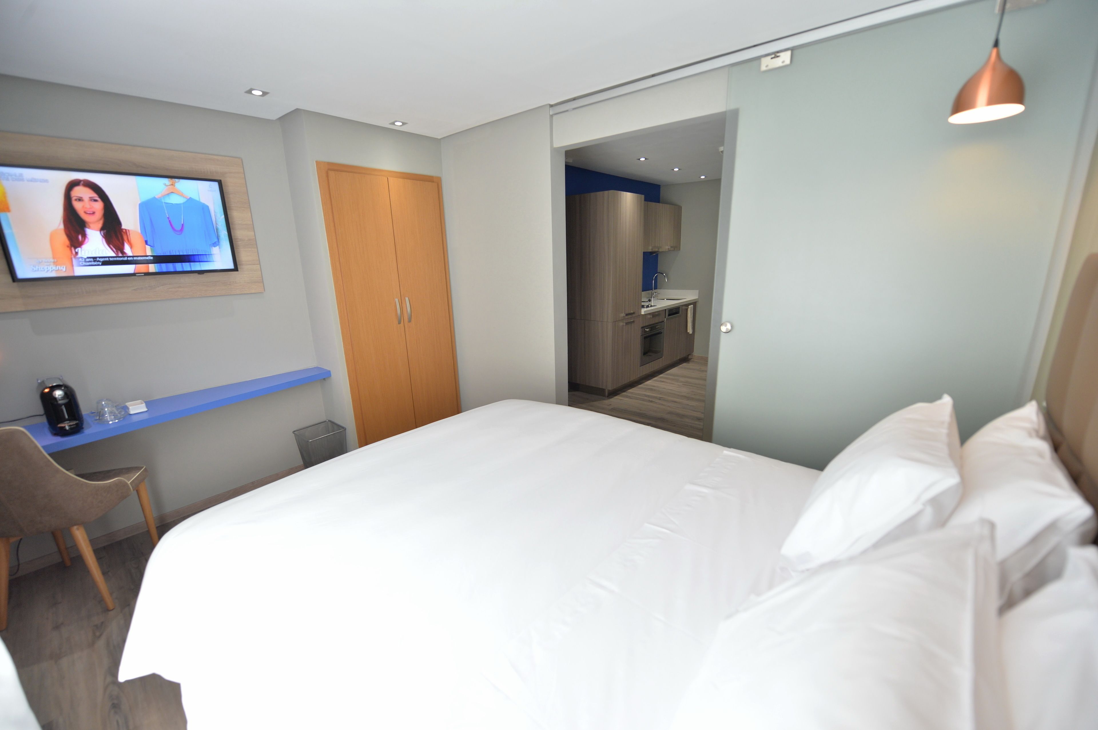 Ein Hotelzimmer mit Bett, Schreibtisch mit Stuhl, Fernseher und einer Küchenzeile.