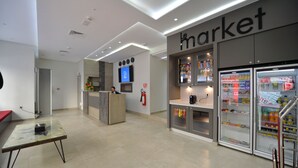 Ein sauberes, modernes Interieur mit einer Rezeption, einer Minibar mit Getränken und einer digitalen Anzeige an der Wand.