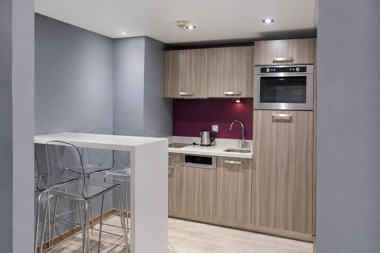 A modern kitchen with wooden cabinets, a stainless steel oven, and a white countertop.