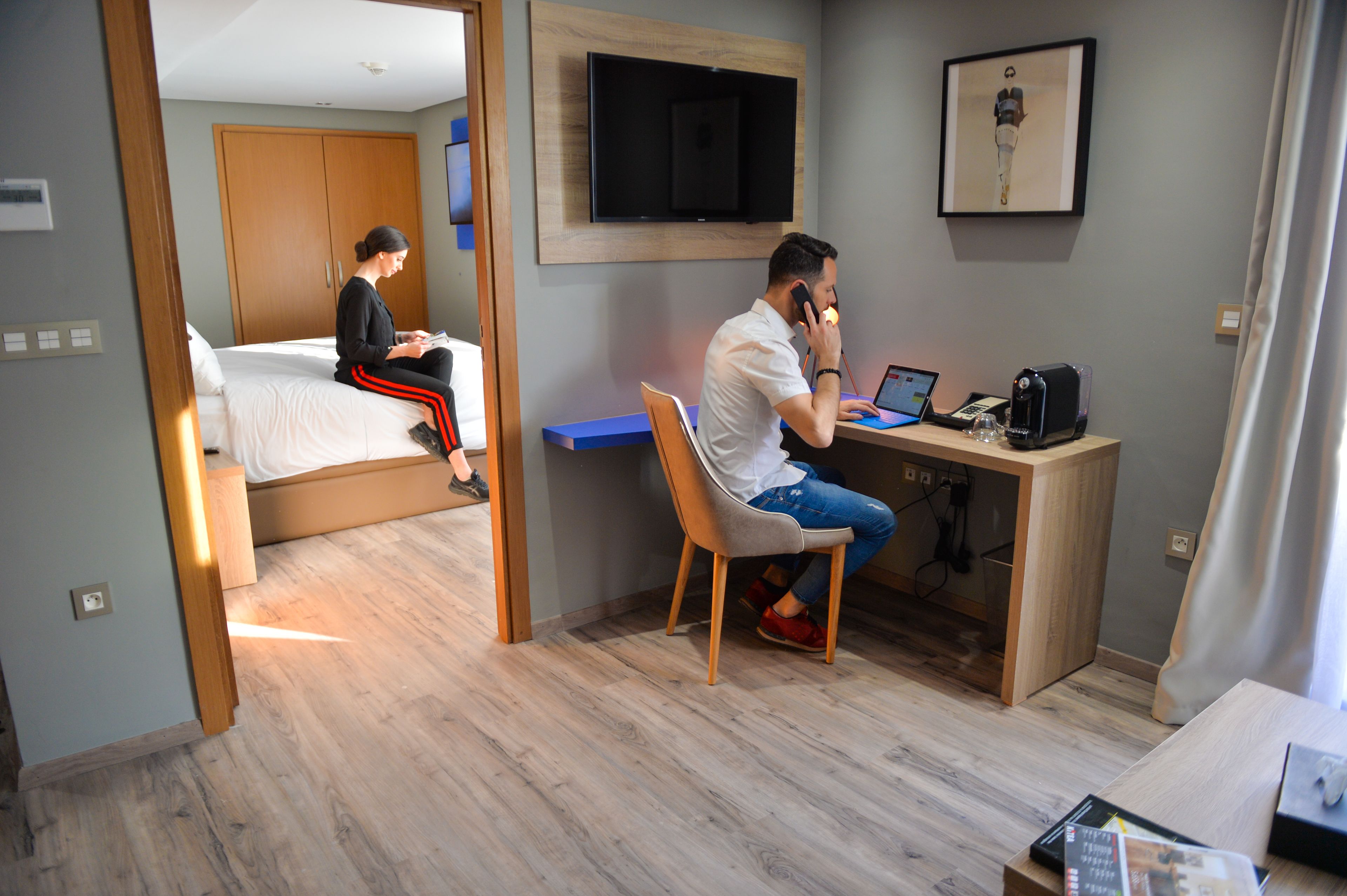Une chambre d’hôtel équipée d’un lit, d’un bureau avec un ordinateur portable et d’un téléviseur fixé au mur.