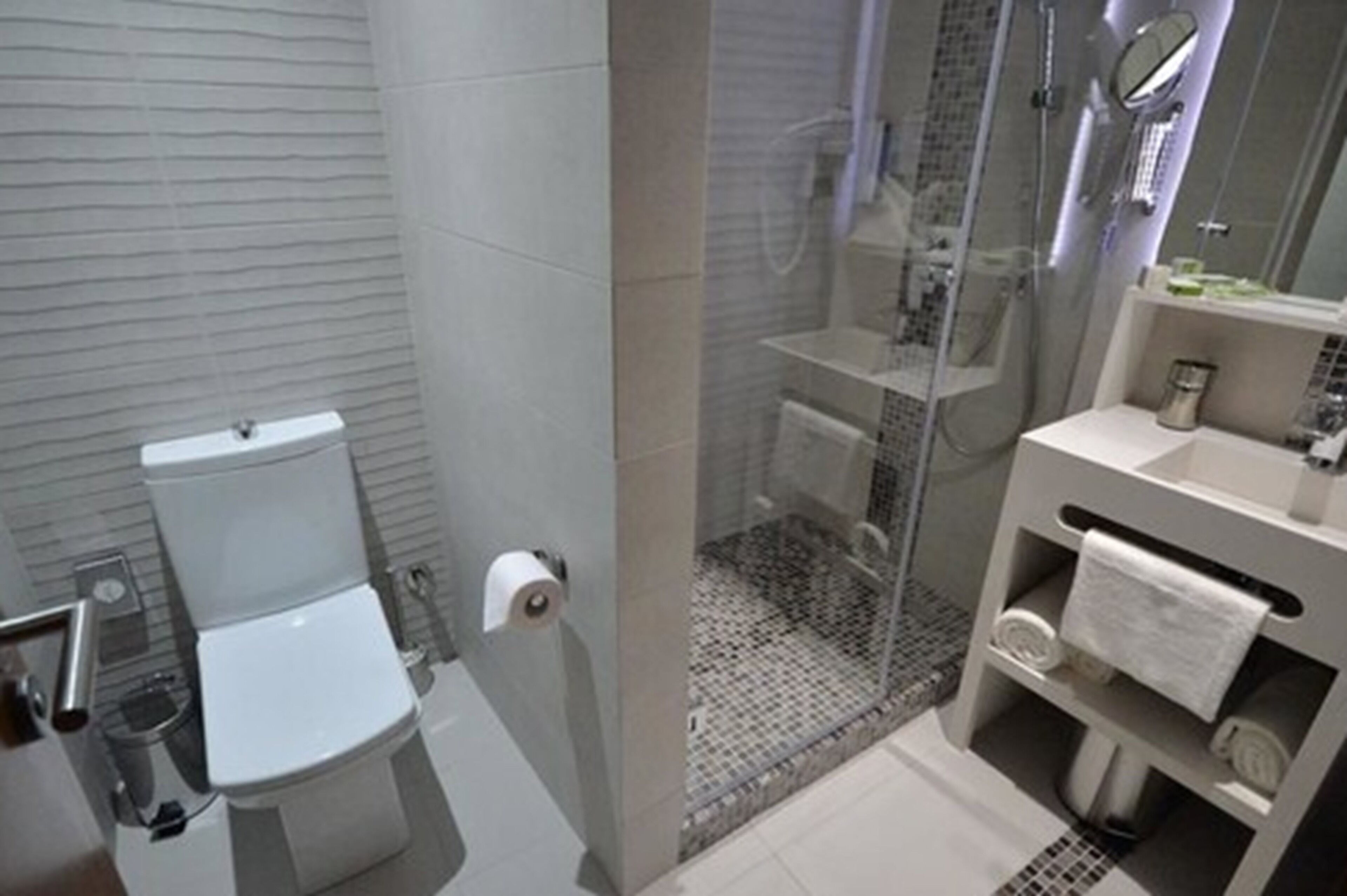 A modern bathroom with a toilet, a glass-enclosed shower, and a vanity with a mirror.