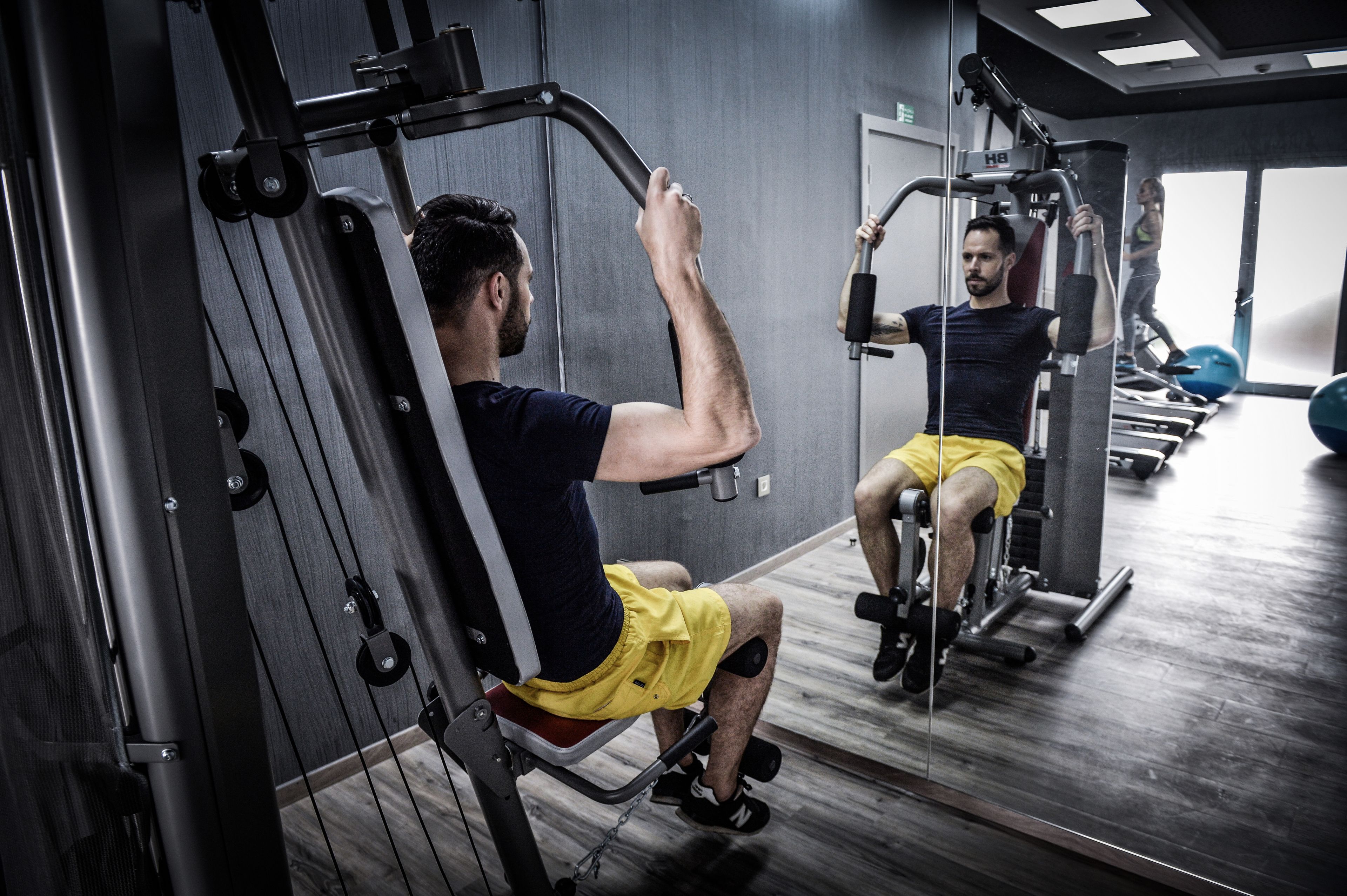 A gym with exercise equipment, a mirror, and a wooden floor.