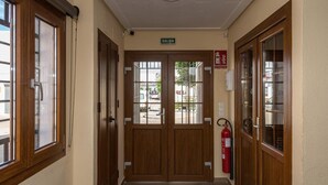 A hallway with wooden doors, a fire extinguisher, and a 'SALIDA' sign. - Hostal Ciudad de Lepe (Lepe)