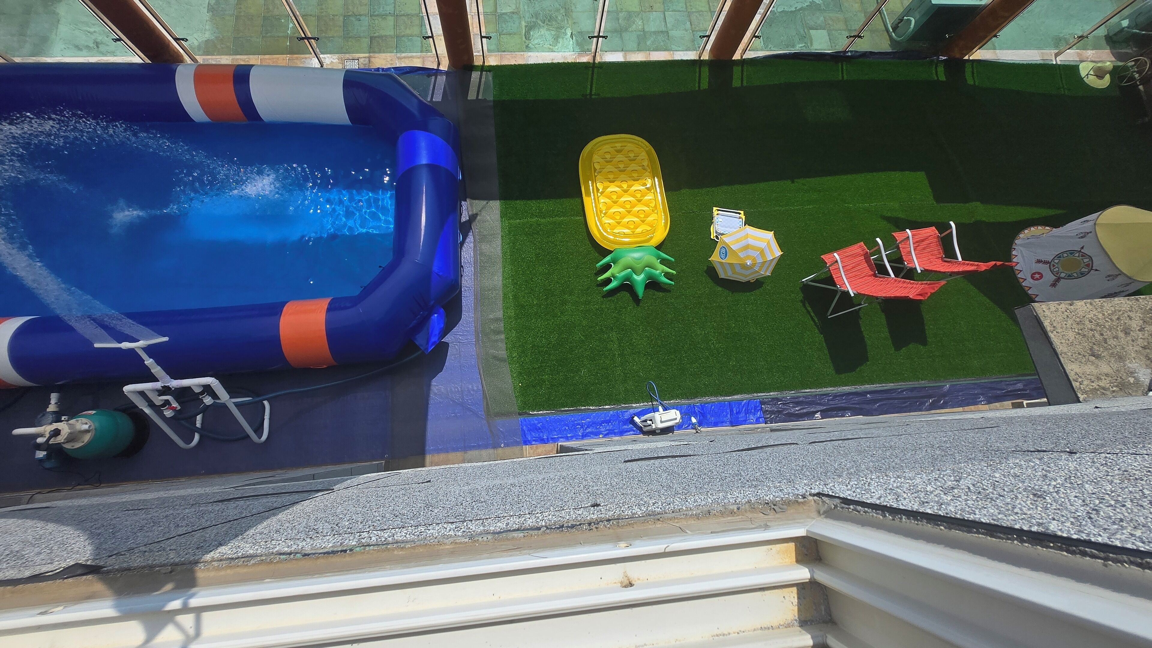 Un espace piscine aménagé sur le toit, avec une piscine gonflable bleue, un fauteuil de plage gonflable jaune et un fauteuil de plage rouge.
