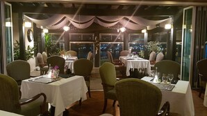 A restaurant with tables set for dining, chairs, and a view of the cityscape at night. - La Belle Hotel In Tongyeong (Tongyeong)