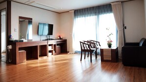 A hotel room with a wooden desk, a flat-screen TV, a sofa, and a large window with curtains. - La Belle Hotel In Tongyeong (Tongyeong)