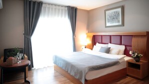 A modern hotel room with a large bed, a bedside table, a nightstand, and a window with curtains. - La Belle Hotel In Tongyeong (Tongyeong)