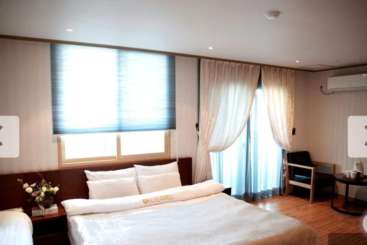 Ein Hotelzimmer mit Bett, Schreibtisch, Stuhl und einem fenster mit Vorhängen.