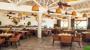 A spacious restaurant with high ceilings, wicker furniture, and pendant lighting. - Royal Beach Hôtel (Nosy Be)