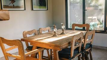 Un comedor con una mesa y sillas de madera, una lámpara colgante y cuadros en la pared.