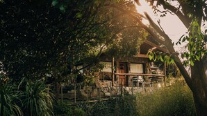 Une maison traditionnelle japonaise, entourée d’une végétation luxuriante et d’un mur de pierre.