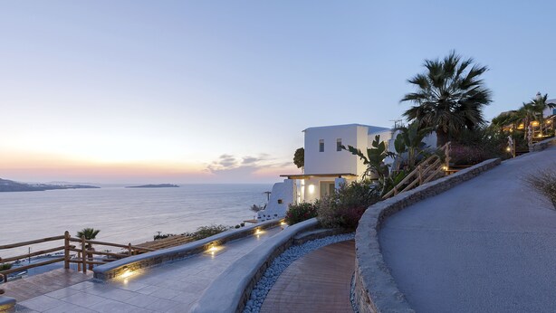 A coastal property with a paved walkway, a wooden fence, and a view of the sea.