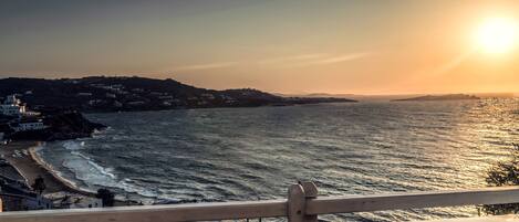 A coastal view with a wooden deck and a railing, overlooking a beach and ocean.