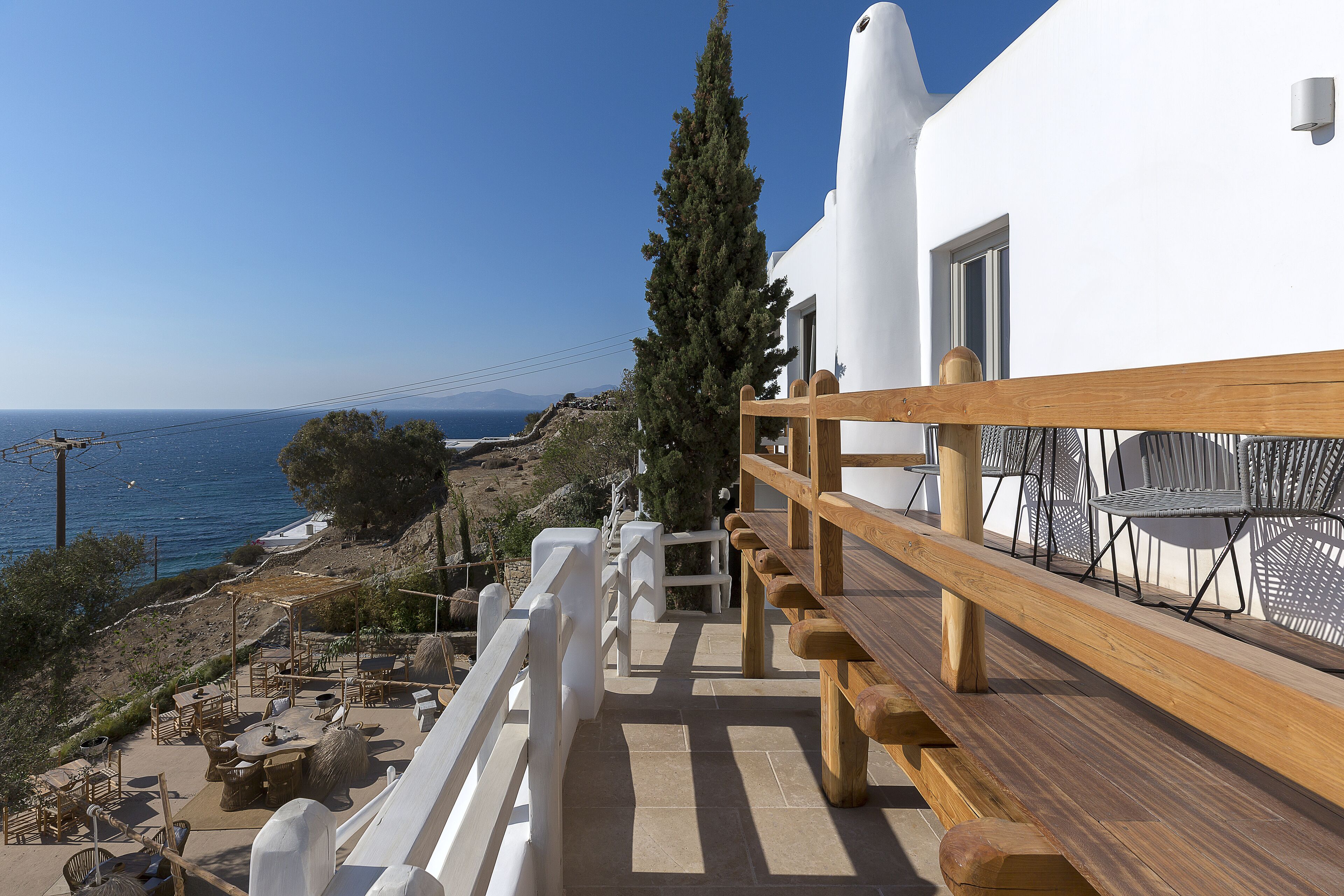 A terrace with outdoor furniture, a wooden railing, and a view of the sea.
