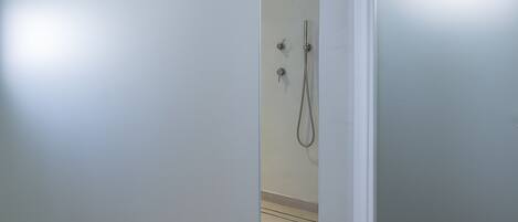 A modern bathroom with a glass partition, a shower, and a frosted door.