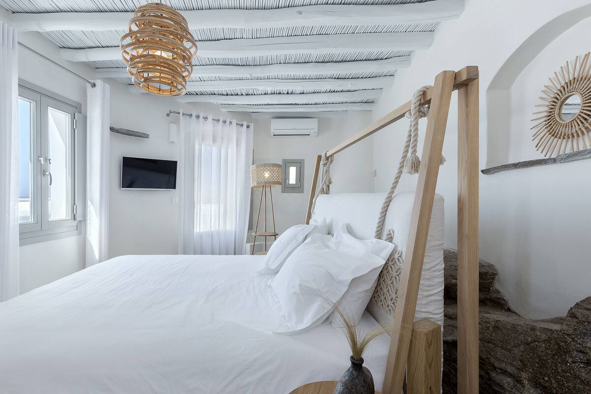 Quarto moderno com uma cama grande, televisão e um design de teto único.