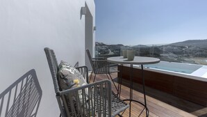 A balcony with wicker chairs, a small table, and a glass-top bathtub.