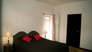 Un dormitorio con cama, dos lámparas de noche, una ventana con cortinas y una puerta.