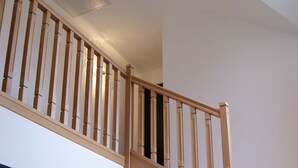 A wooden staircase with a handrail and a light fixture on the wall. - La Grange de Salomé (Salomé)