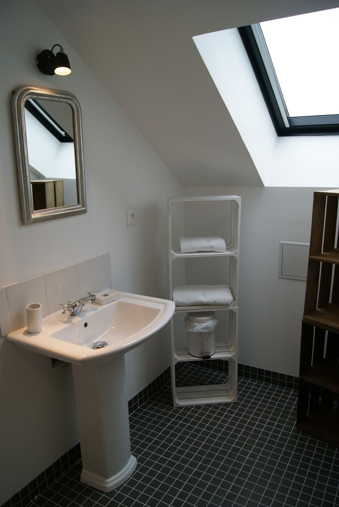 Een badkamer met een wit wastafel, spiegel en planken.
