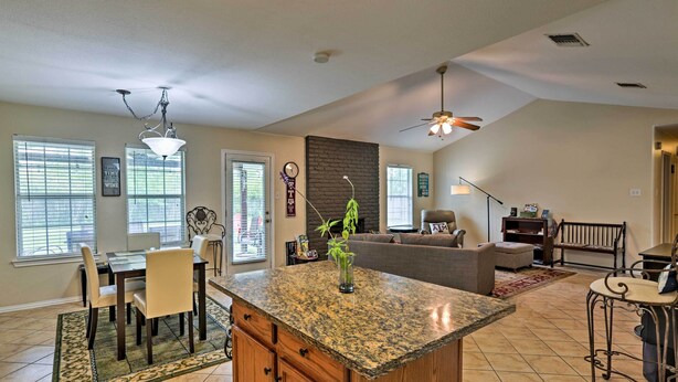 A spacious kitchen with granite countertops, a dining area with chairs, a living room with a sofa, and a ceiling fan. - 2 Mi to Lake McQueeny: Gem w/ Covered Patio (McQueeney)