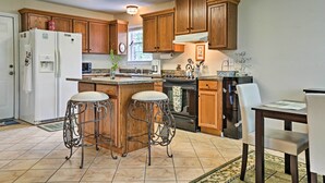 A kitchen with wooden cabinets, a refrigerator, a stove, and two bar stools. - 2 Mi to Lake McQueeny: Gem w/ Covered Patio (McQueeney)