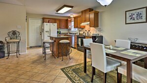 A kitchen with wooden cabinets, a refrigerator, a microwave, and a dining area with a table and chairs. - 2 Mi to Lake McQueeny: Gem w/ Covered Patio (McQueeney)