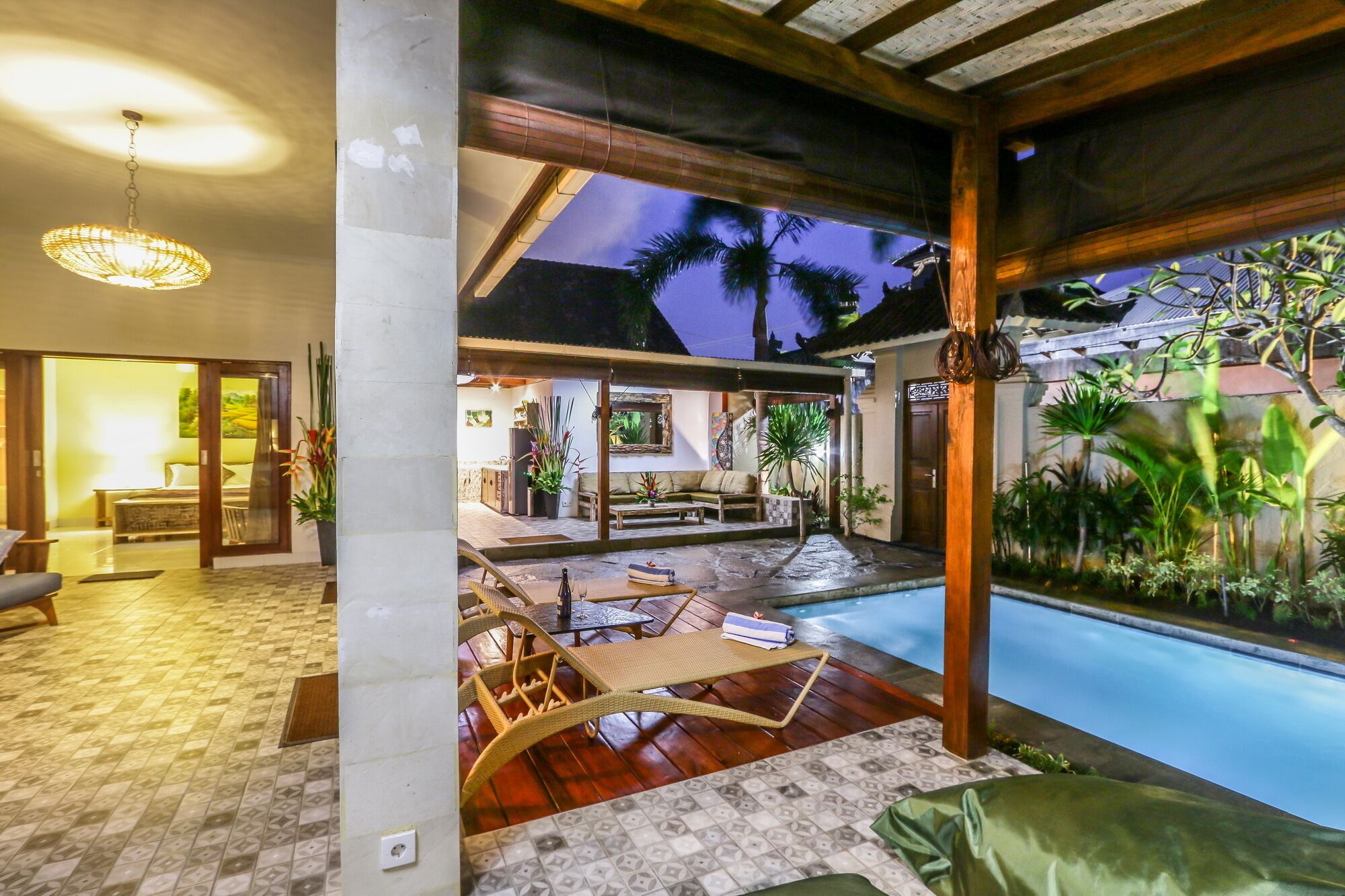 A spacious indoor area with a pool, wooden flooring, and a view of the outdoors.