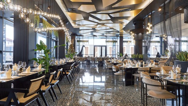 Un restaurant spacieux avec de hauts plafonds, des lustres modernes et un sol en marbre poli.