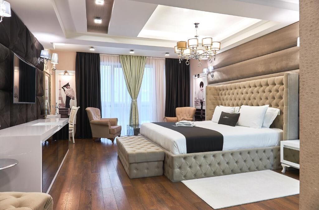 A modern hotel room with a large bed, a desk, and a seating area.