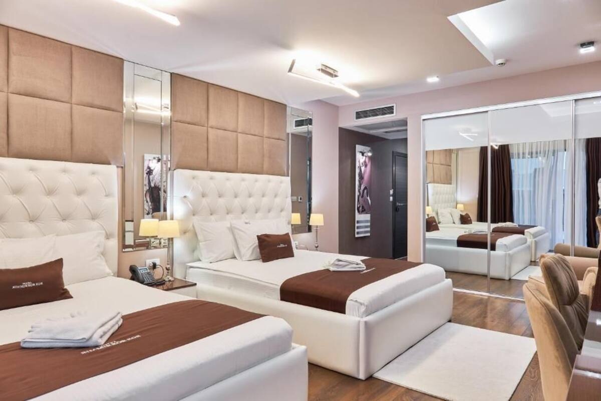 A hotel room with two beds, a large mirror, and a seating area.